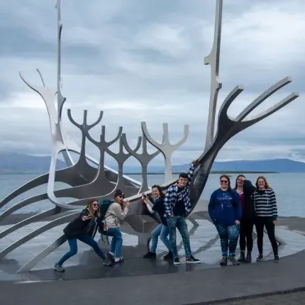 Several students stand in front of a steel sculpture of a viking ship on Reykjavik's waterfront